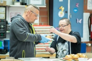 Betreuer übergibt Brötchen an Klienten