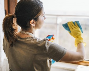 Reinigungskraft putzt Fenster